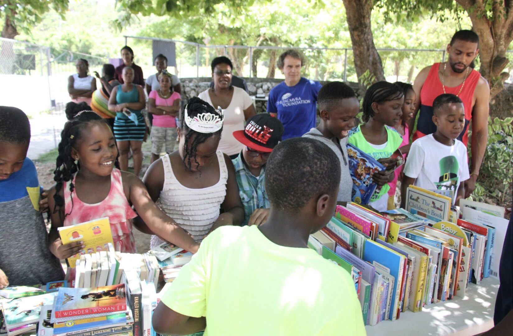 A group of children standing around a table full of books.