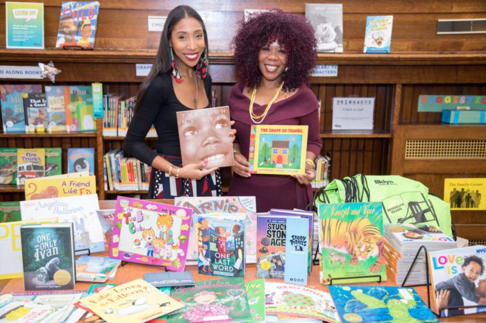 Two women standing in front of a table full of books.