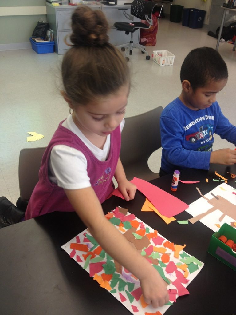 A group of children are making paper crafts at a table.