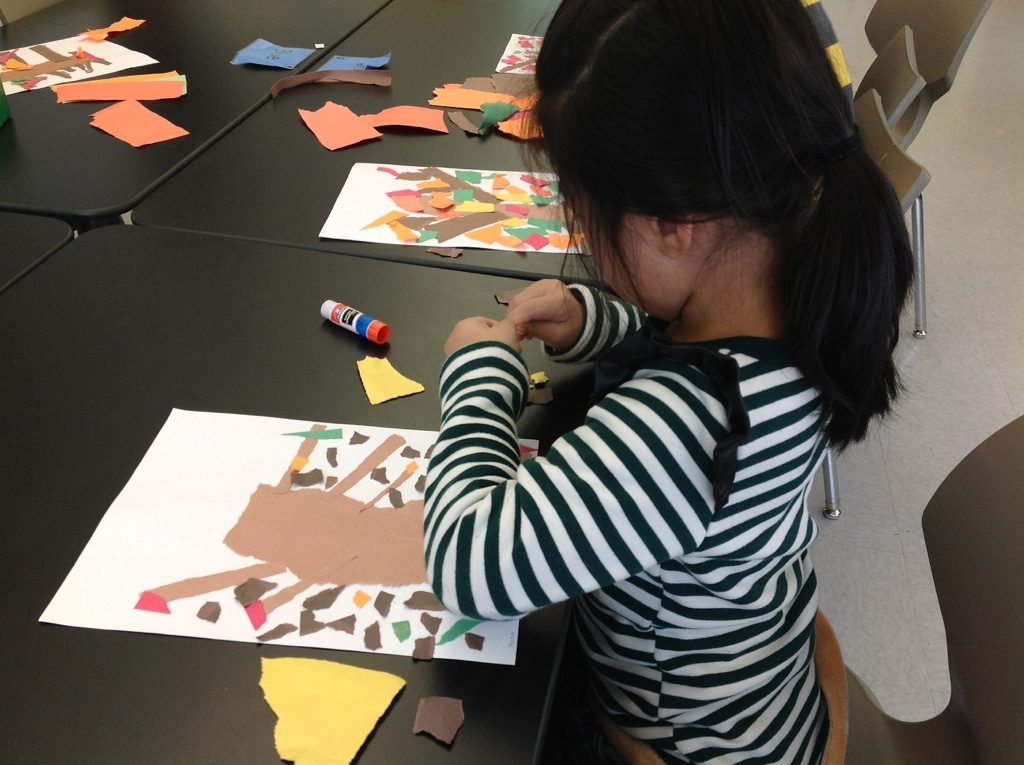 A girl is making paper crafts in a classroom.