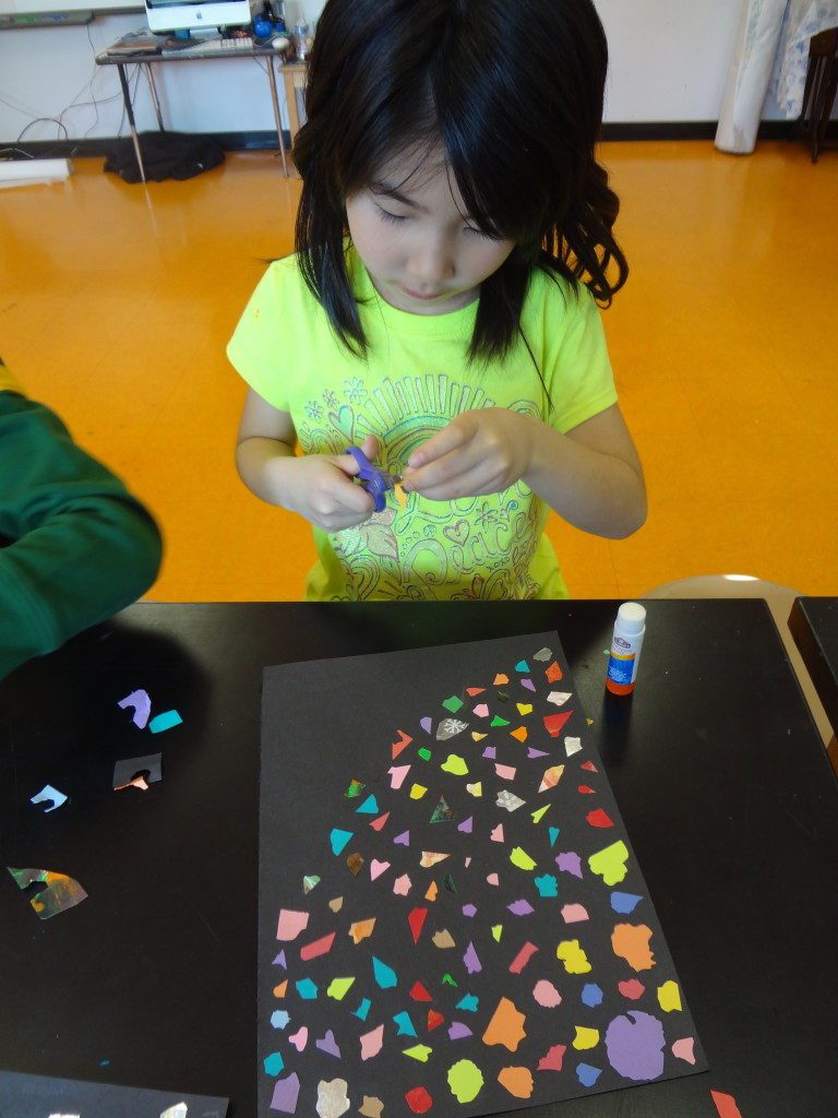 A little girl is making a paper craft.