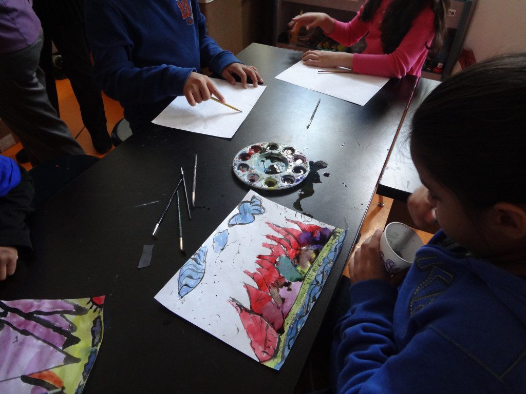 A group of children are sitting at a table making art.