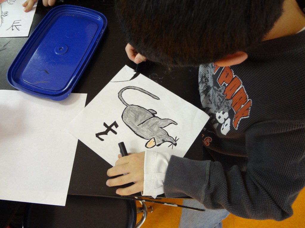 A boy is drawing a picture of a rat.
