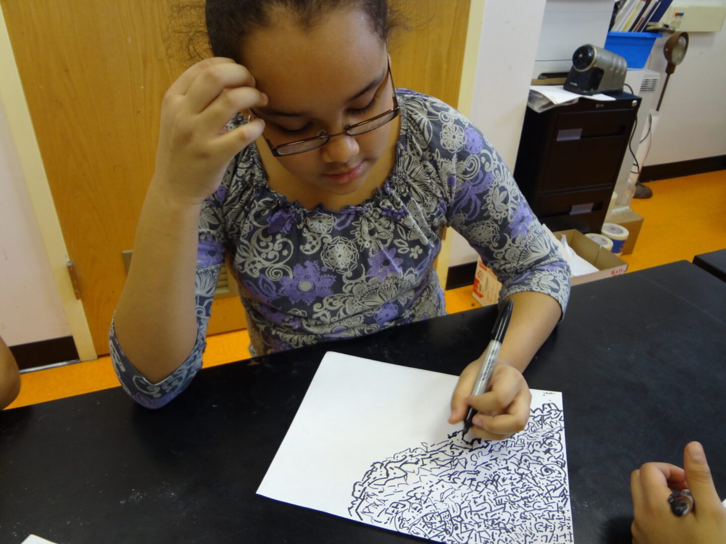 A girl is drawing on a piece of paper.