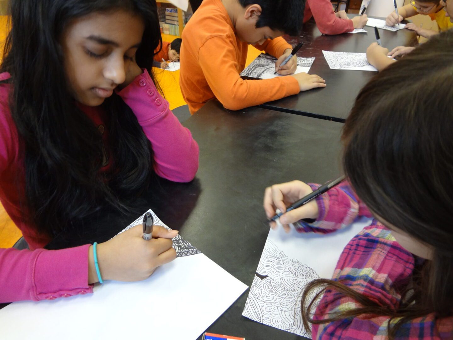 A group of kids drawing on paper in a classroom.