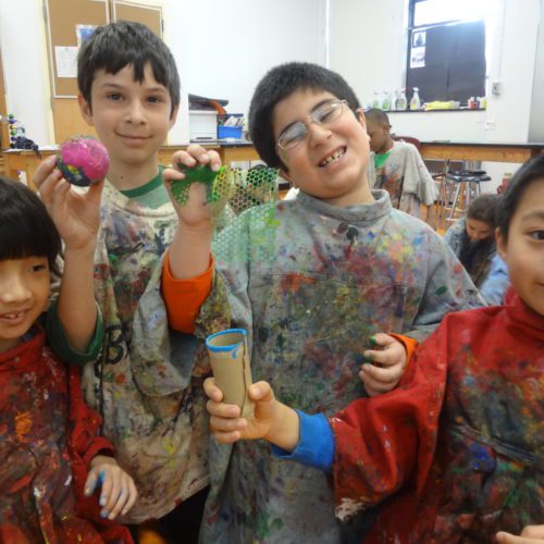 A group of kids in a classroom with paint on their faces.