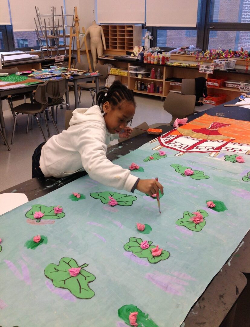 A girl is painting on a large piece of paper.