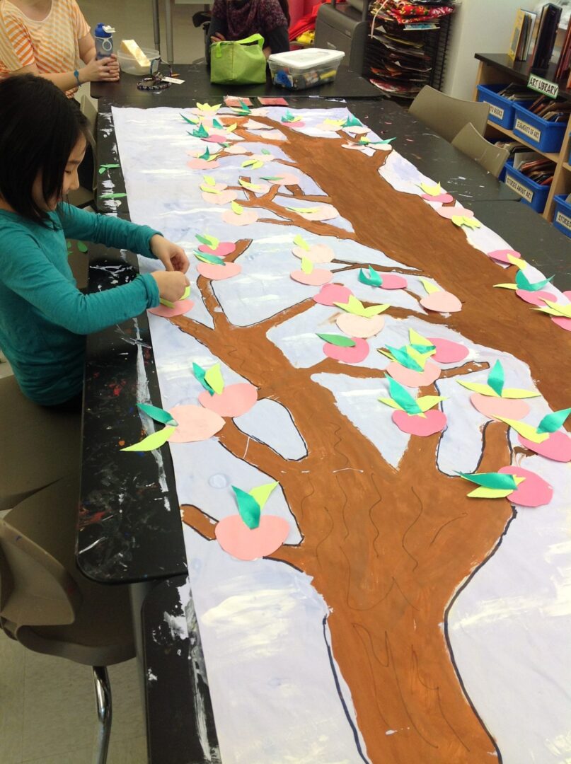 A girl is making a tree out of paper.
