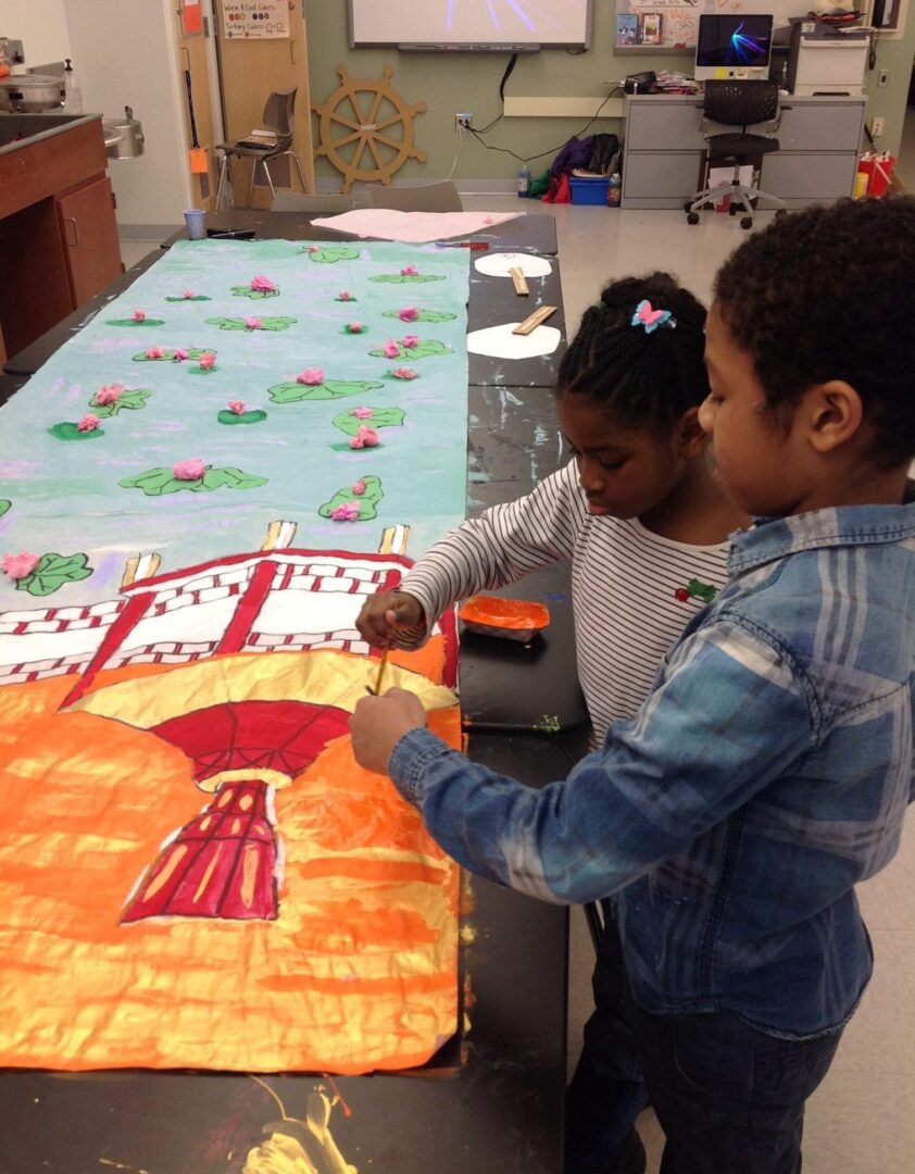 Two toddlers painting an art with orange color