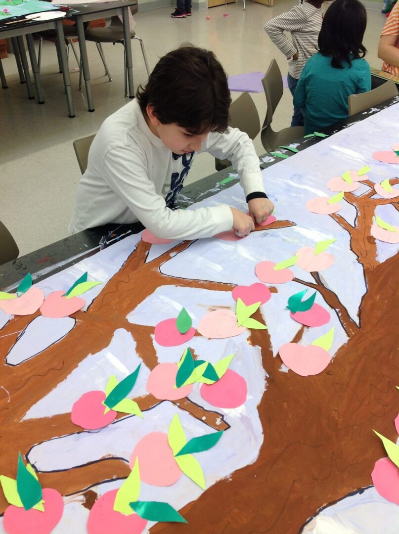 A boy is working on a paper tree.