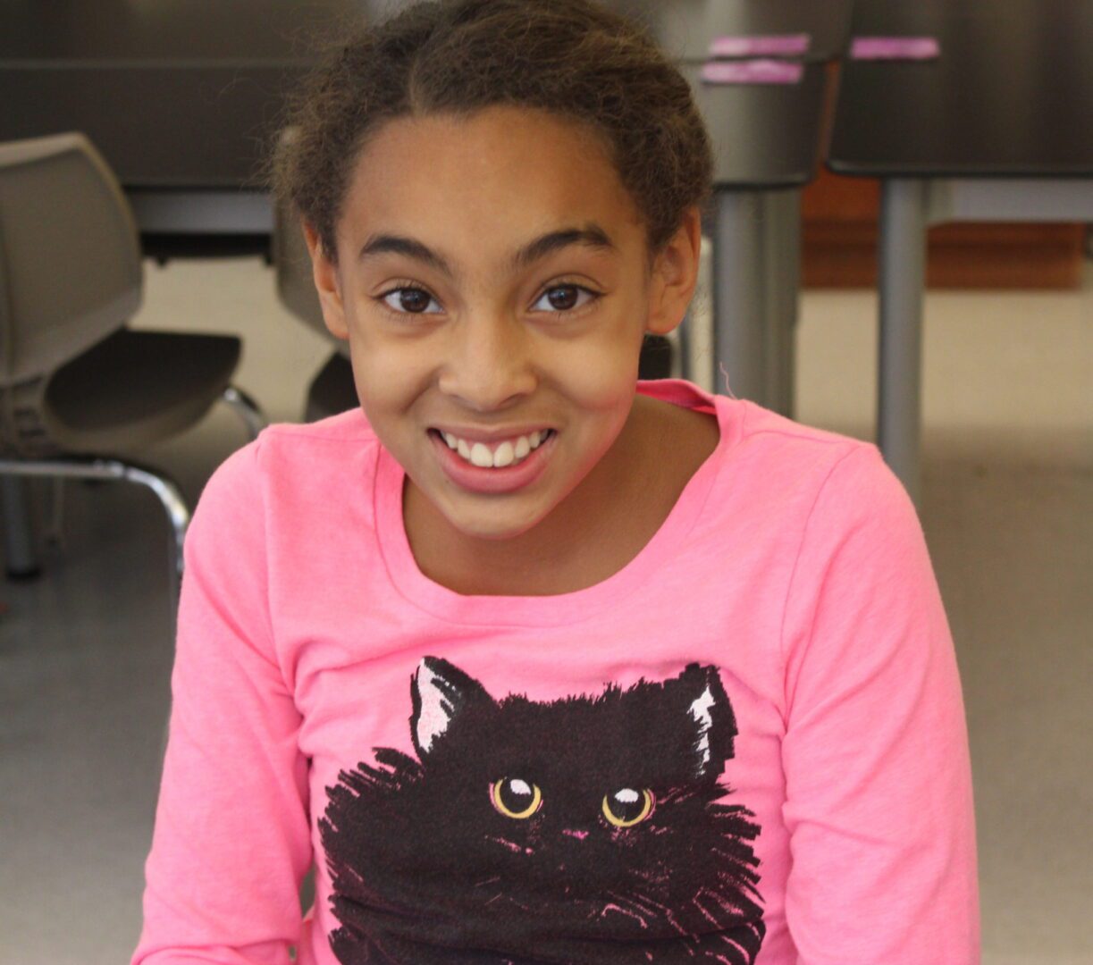 A girl wearing a pink shirt with a cat on it.
