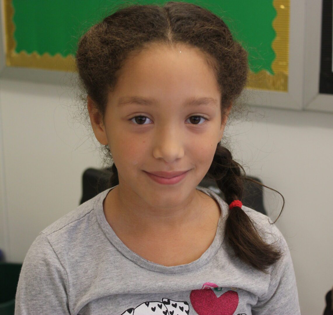 A young girl wearing a tee shirt with a heart on it.