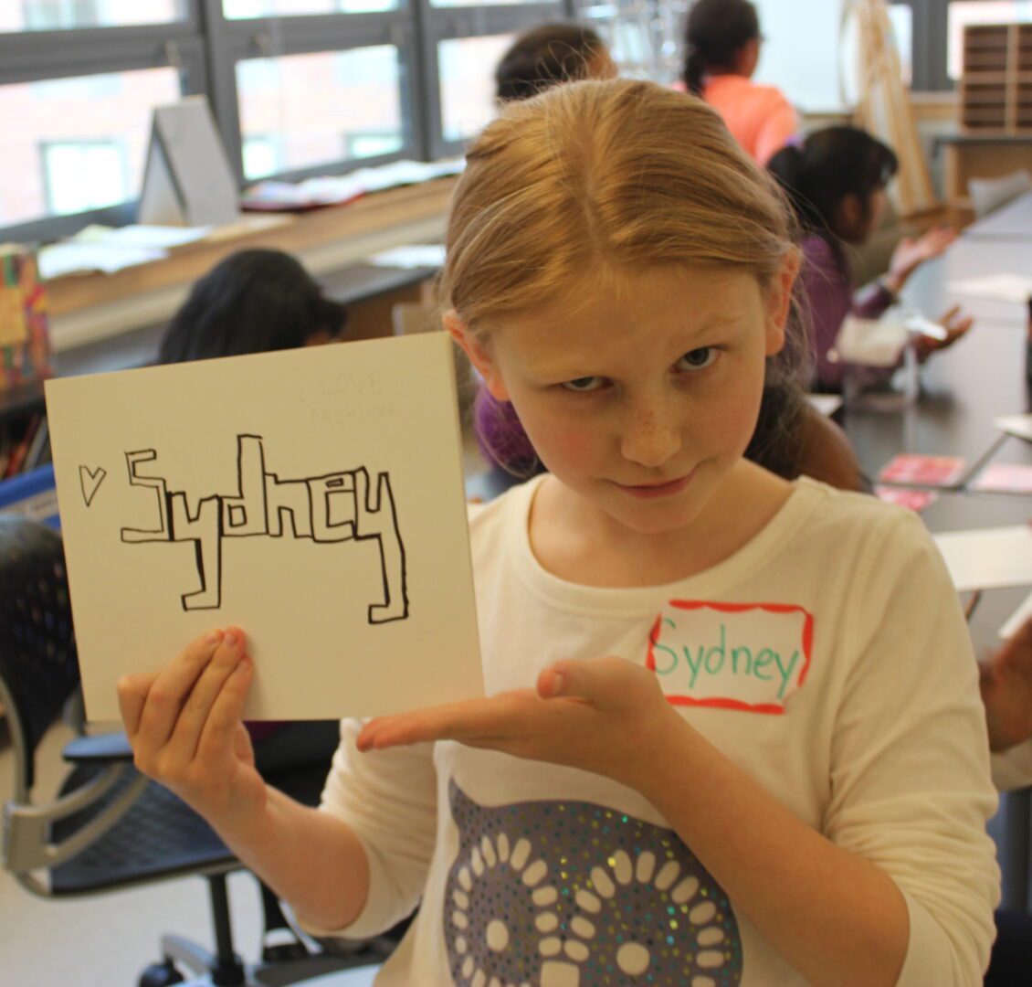 A girl holding up a drawing.