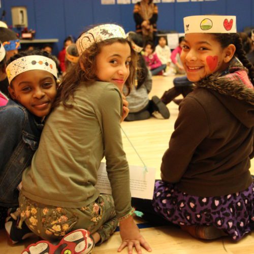 A group of girls sitting on the floor with crowns on their heads.