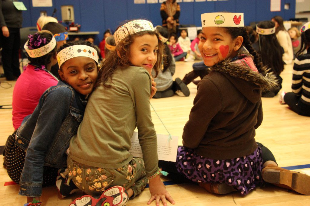 A group of girls sitting on the floor with crowns on their heads.