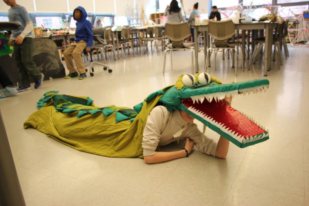 A boy laying on the floor with a crocodile costume.
