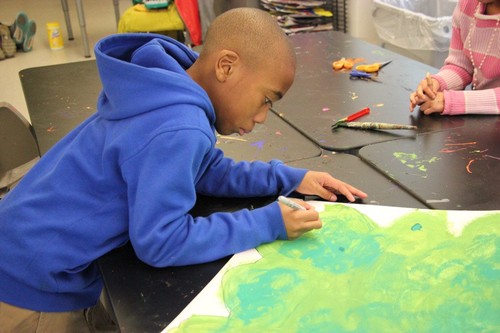 A boy is working on a painting at a table.