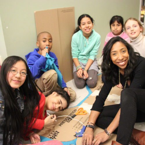 A group of children sitting on the floor with cardboard boxes.