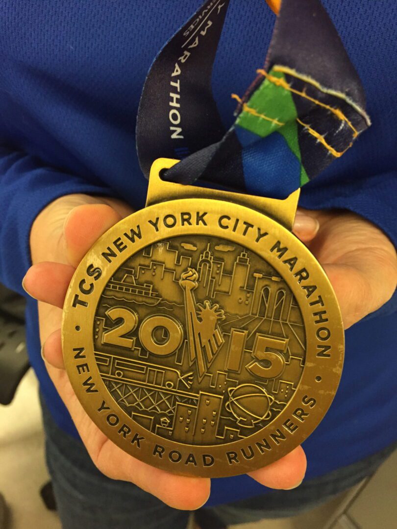 A woman holding a medal for the new york city marathon.