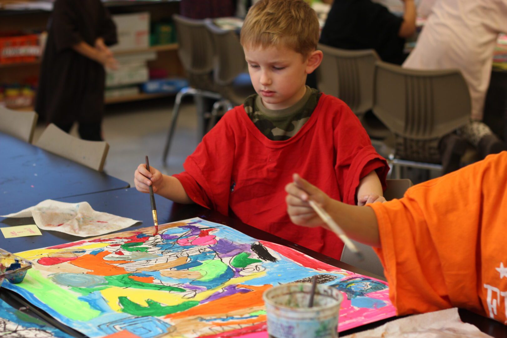 A young boy is painting a painting in a classroom.