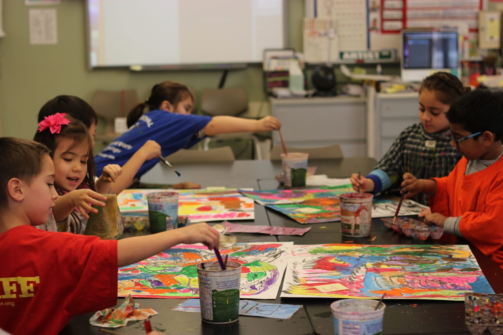 A group of kids painting on a table.
