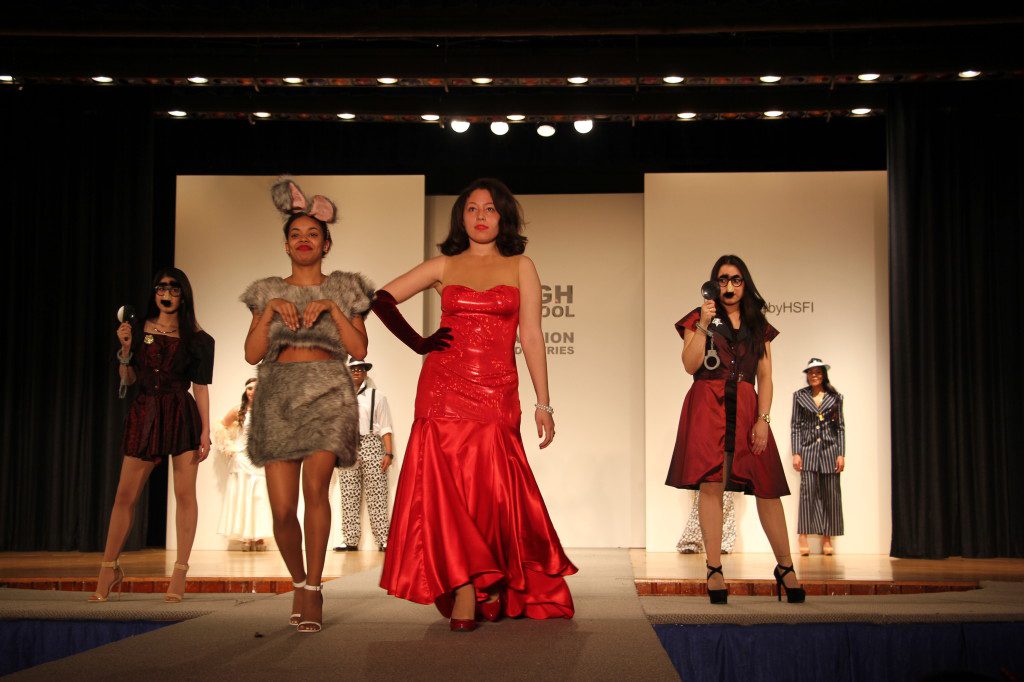 A group of women on a runway in a red dress.
