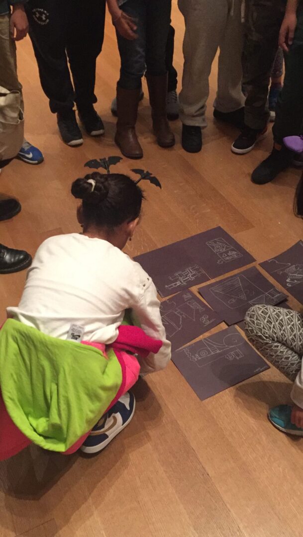 A group of people sitting on the floor and drawing on paper.