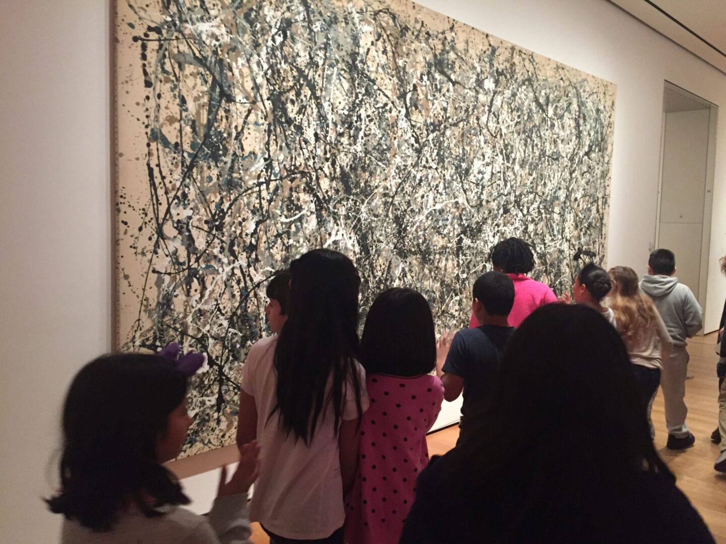 A group of children looking at a painting in an art museum.