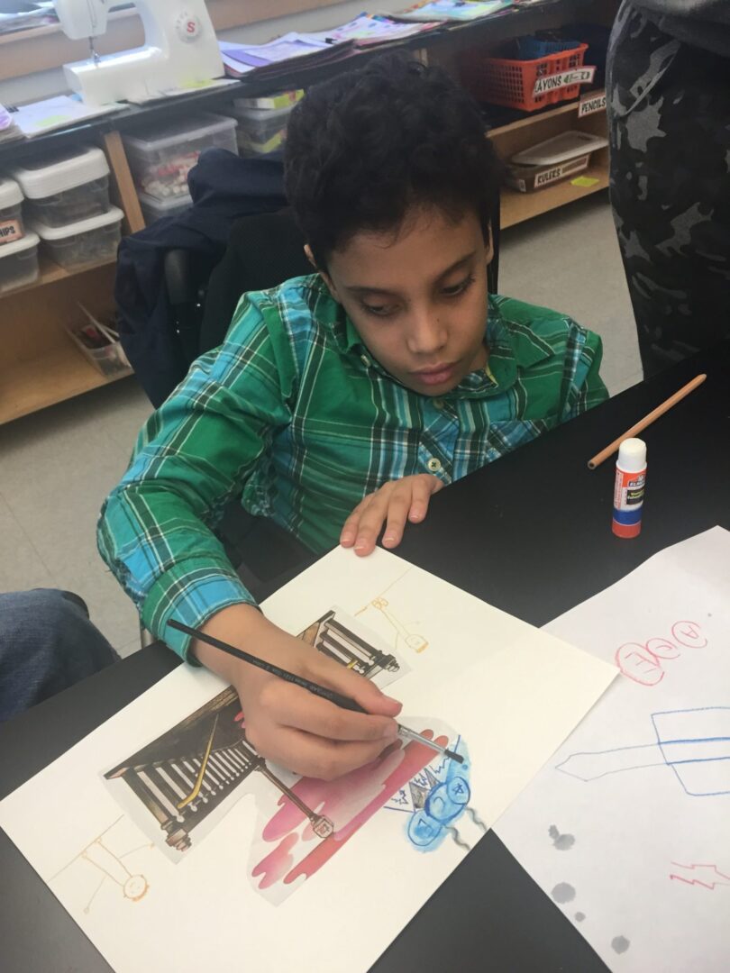 A boy is drawing on a piece of paper.
