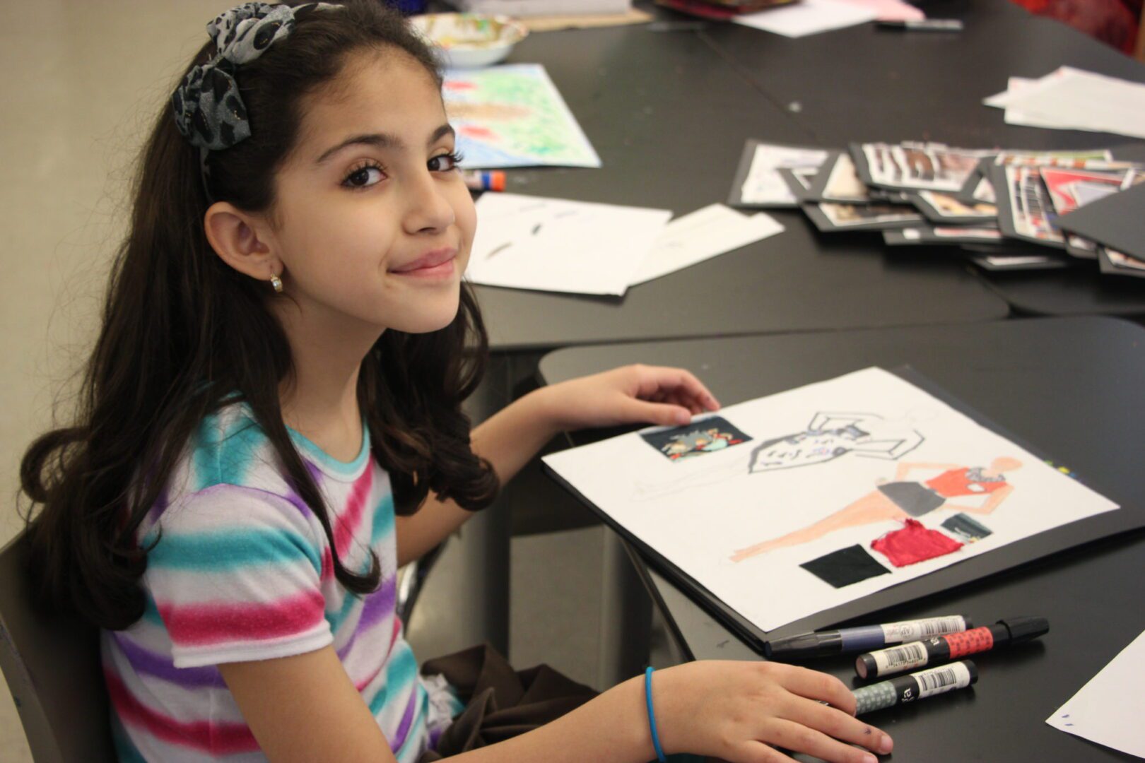 A young girl sitting at a table drawing a picture.