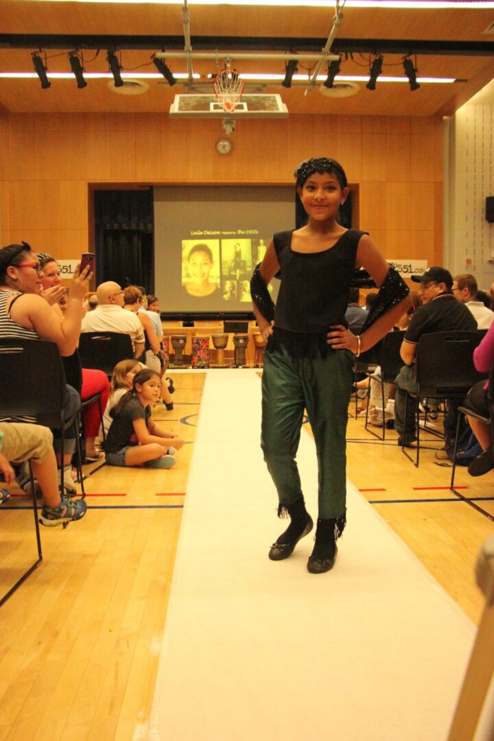 A girl is walking down a runway in front of a crowd of people.