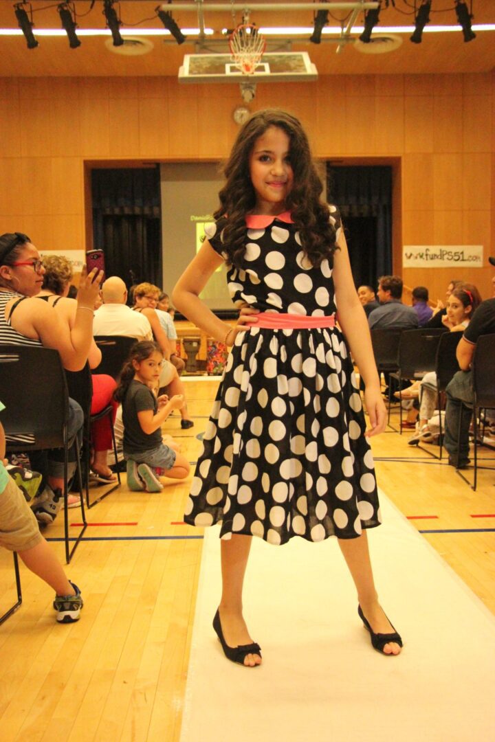 A girl in a polka dot dress on a runway.