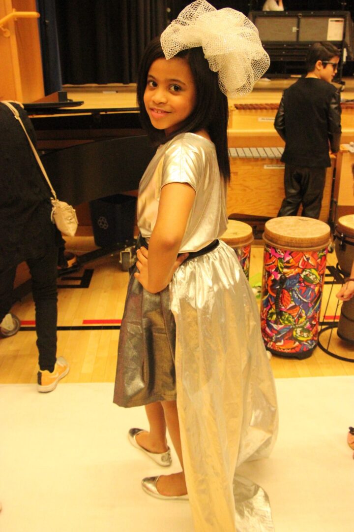 A young girl in a silver dress posing for a picture.