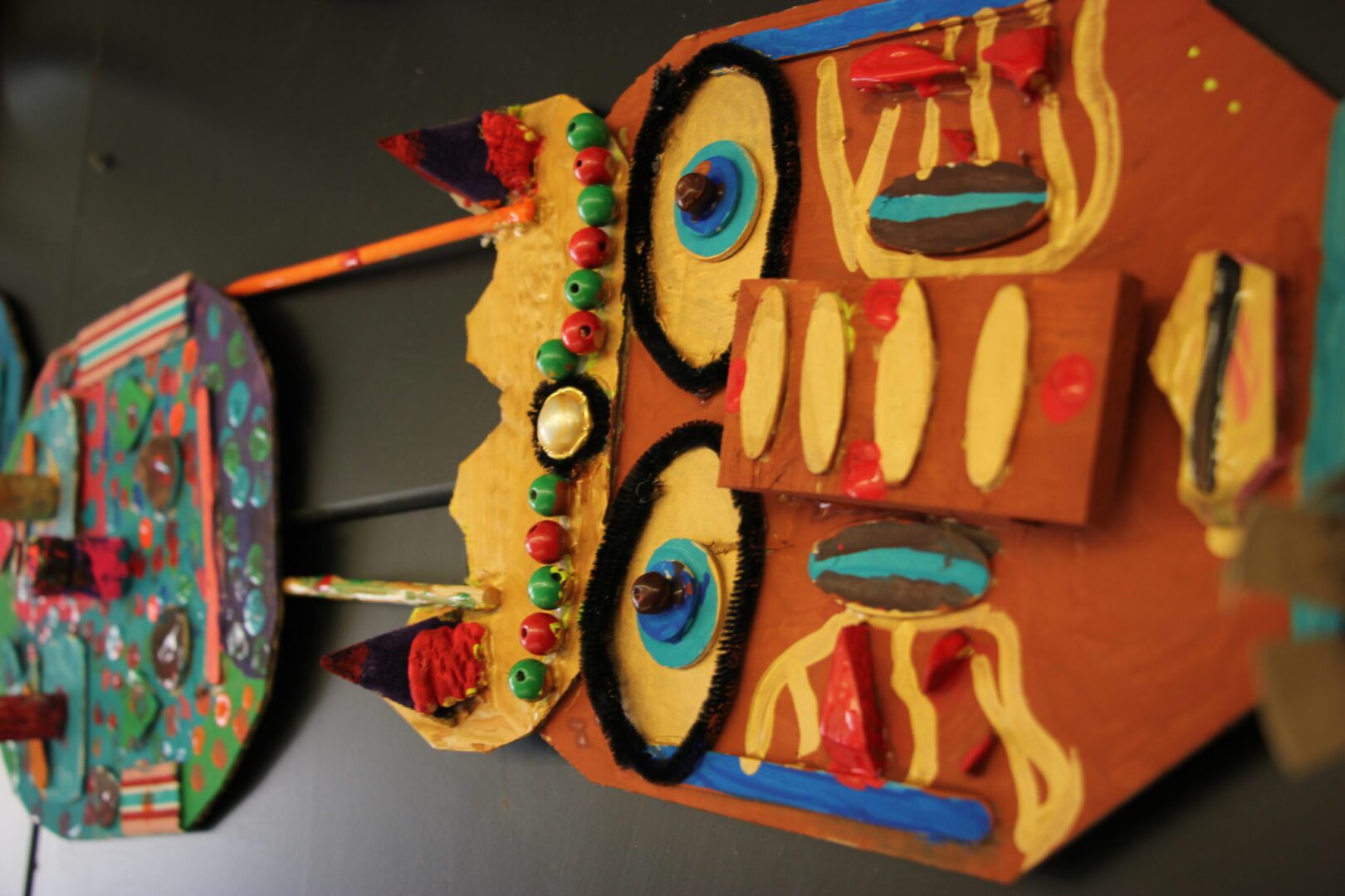 A group of papier mache masks hanging on a wall.