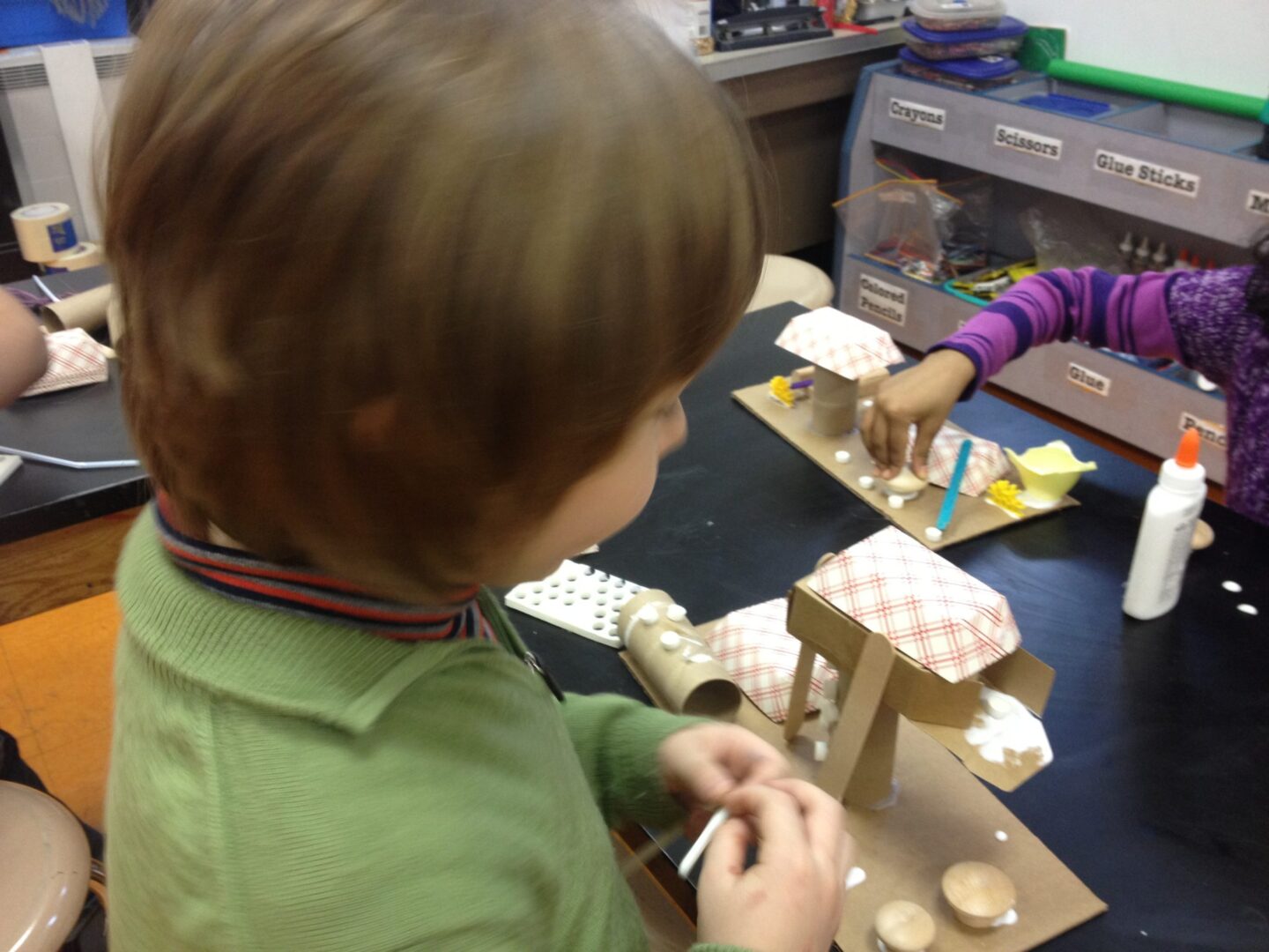 A young boy is making a paper model of a horse.
