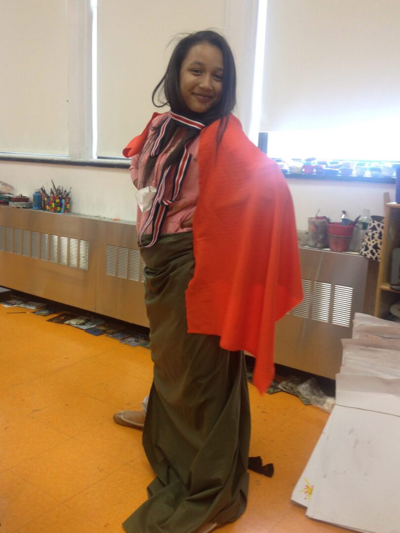 A woman wearing a cape in a classroom.