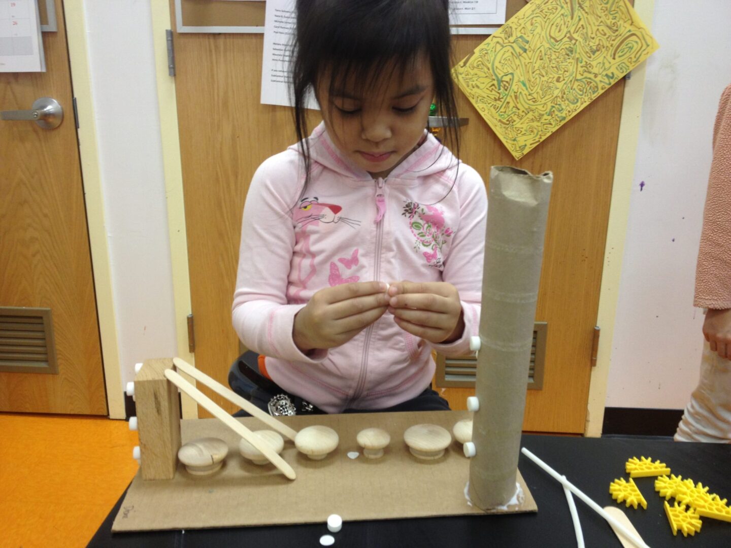 A girl is making a model of a bridge out of paper.