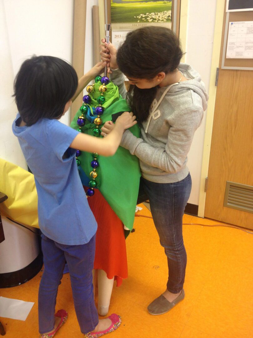 Two girls are putting on a dress.