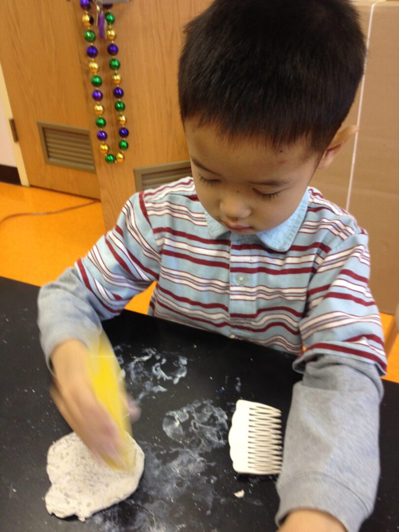 A young boy is making a dough with a brush.