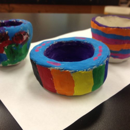 Three colorfully painted cups on a piece of paper.