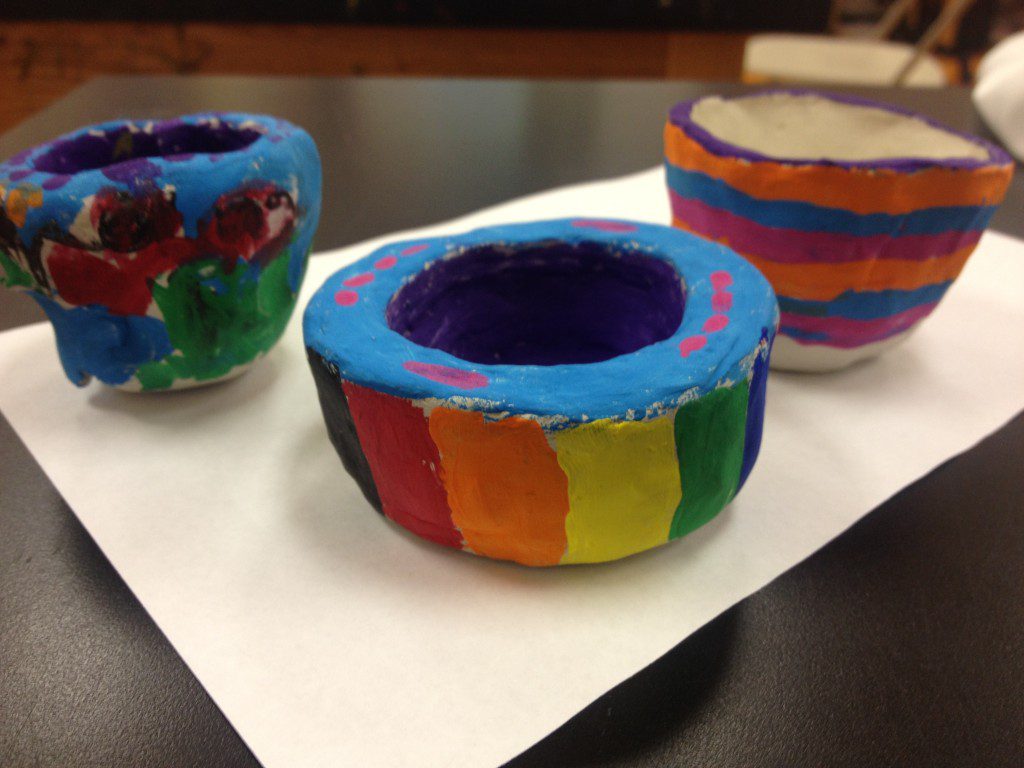 Three colorfully painted cups on a piece of paper.