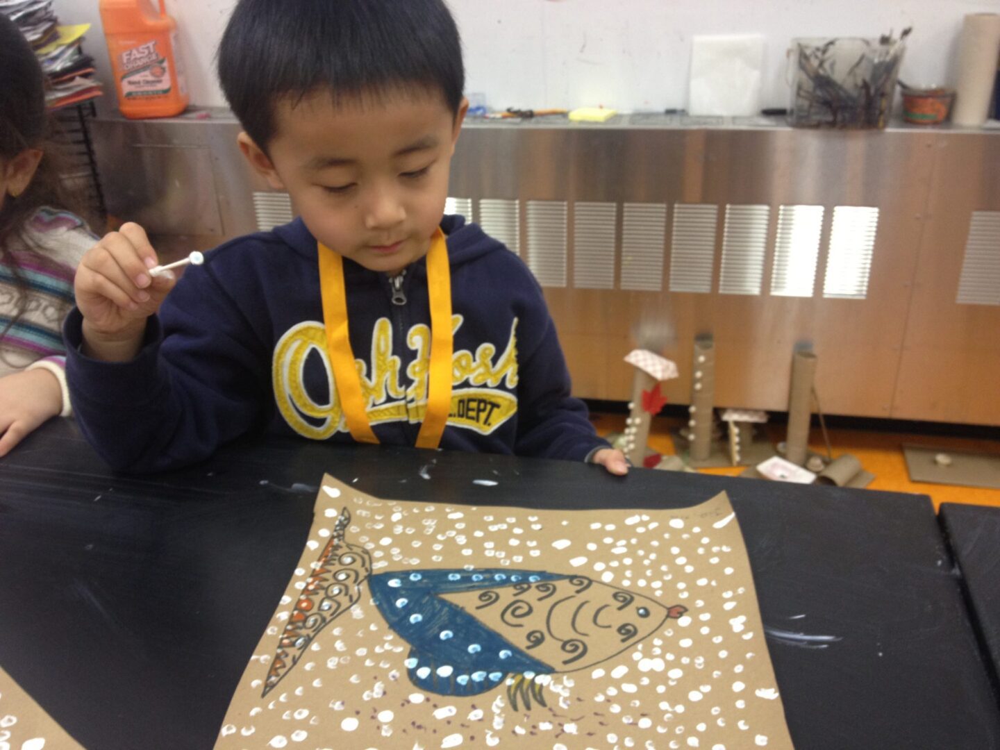 A young boy is painting a fish on a piece of paper.
