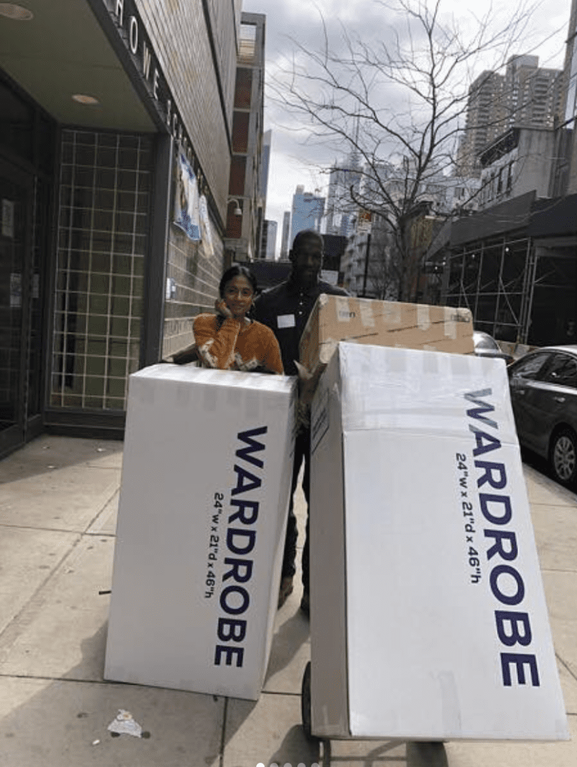 Two people standing on a sidewalk with boxes in front of them.