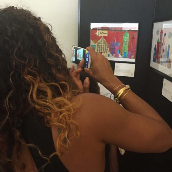 A woman taking a picture of her artwork.