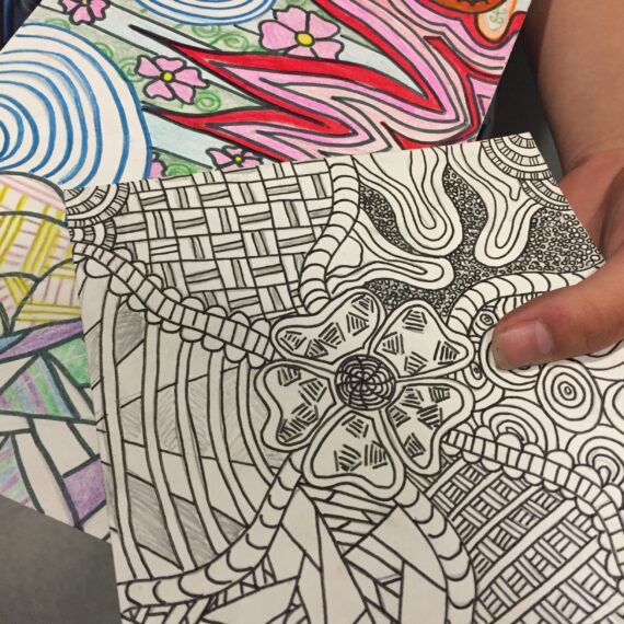 A person holding a coloring book with designs on it.