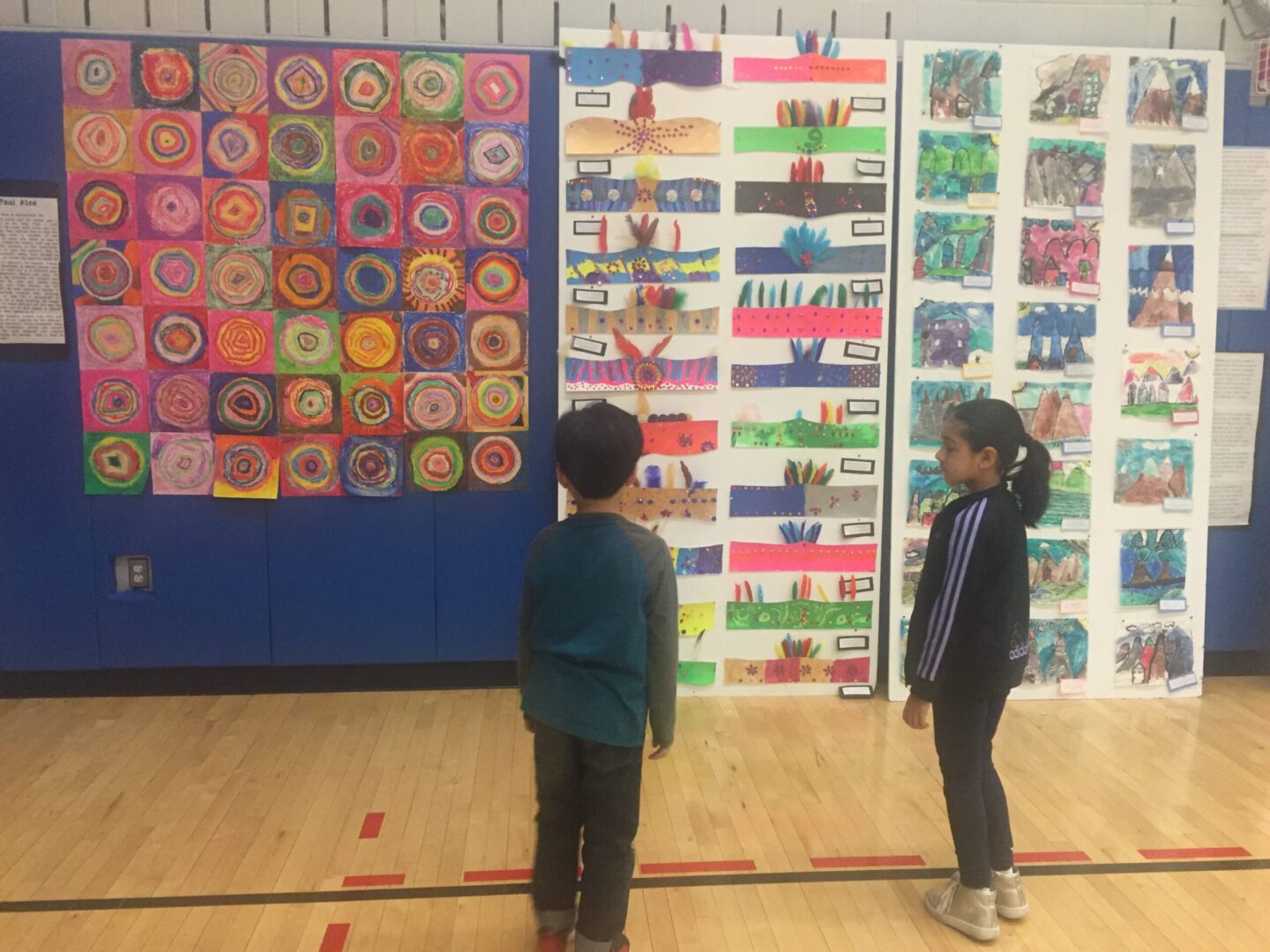 Two children standing in front of a display of art work.