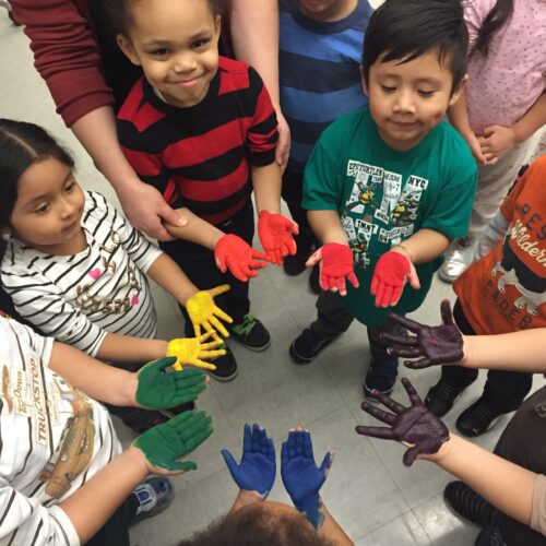 A group of children in a circle with colorful paint on their hands.