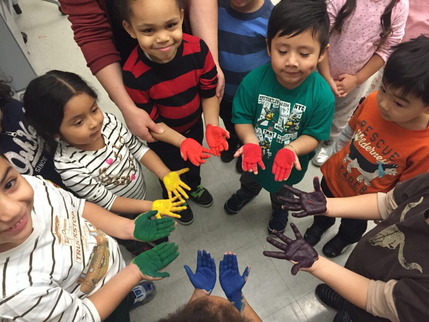 A group of children in a circle with colorful paint on their hands.