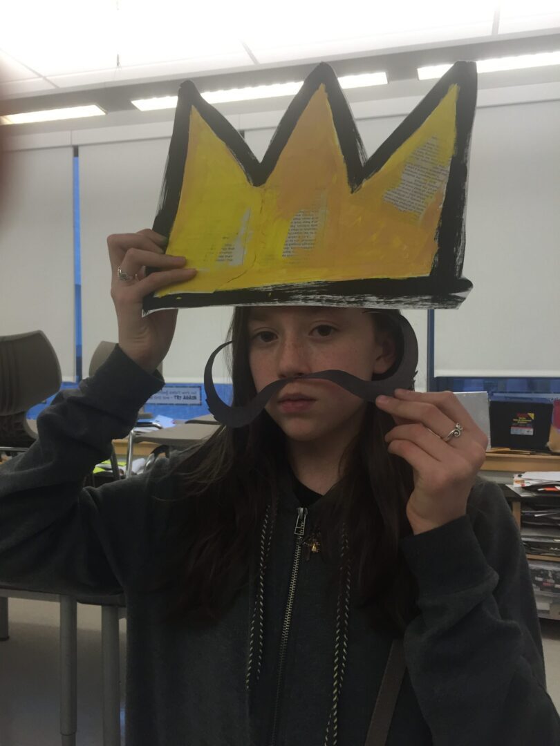 A girl wearing a crown with a mustache.