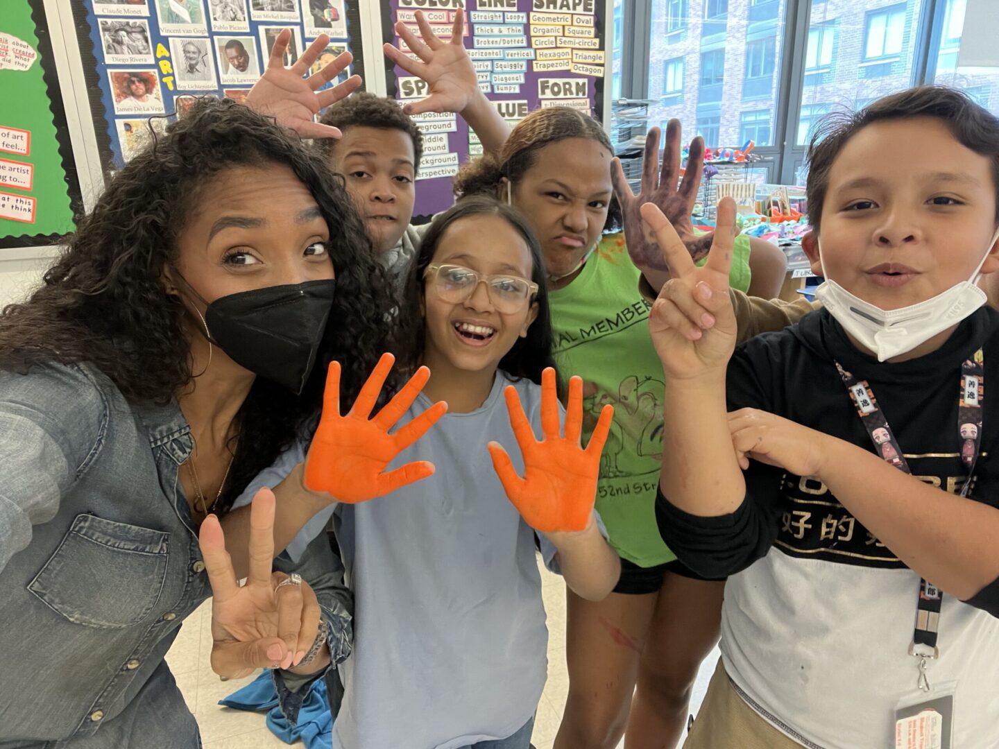 A group of children posing for a photo with their hands painted orange.